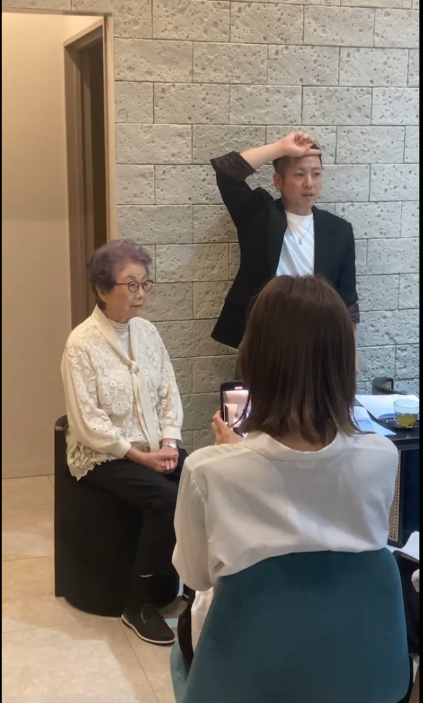アトリエMIHOでの臨店講習で、着席したモデルの頭に手を添えて実演する久保鉄平