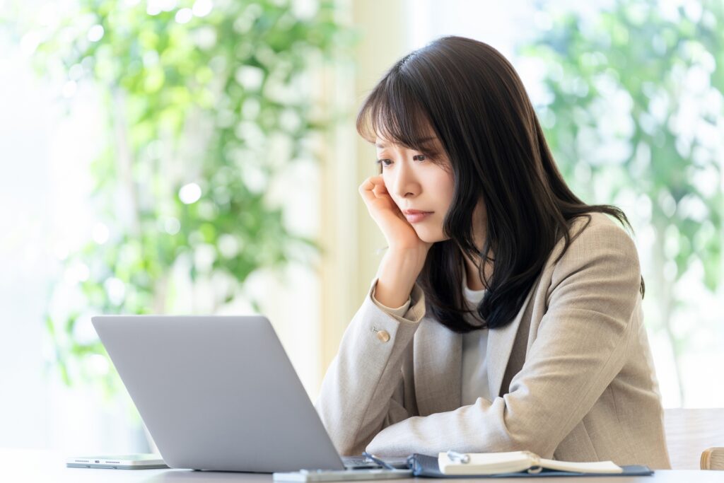 長時間のデスクワークで目と頭に疲れを感じている女性