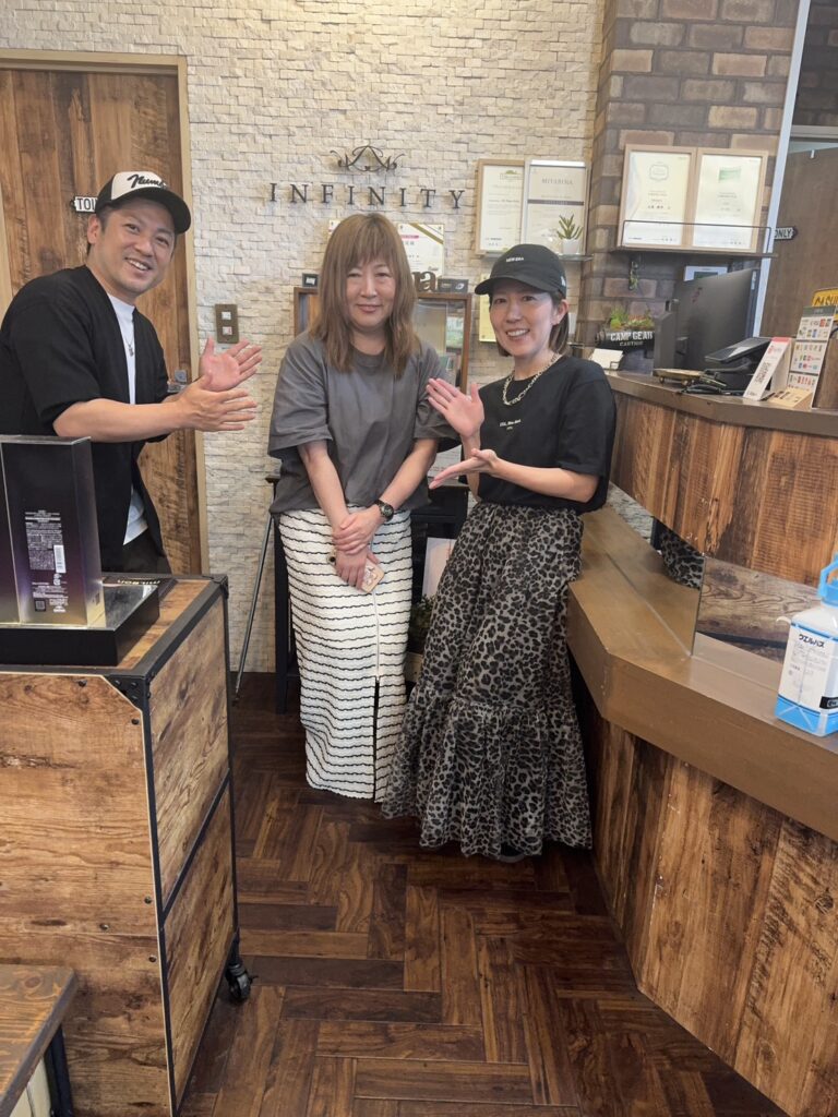 INFINITYの受付前で撮影した導入相談のサロン関係者と久保鉄平らの記念写真