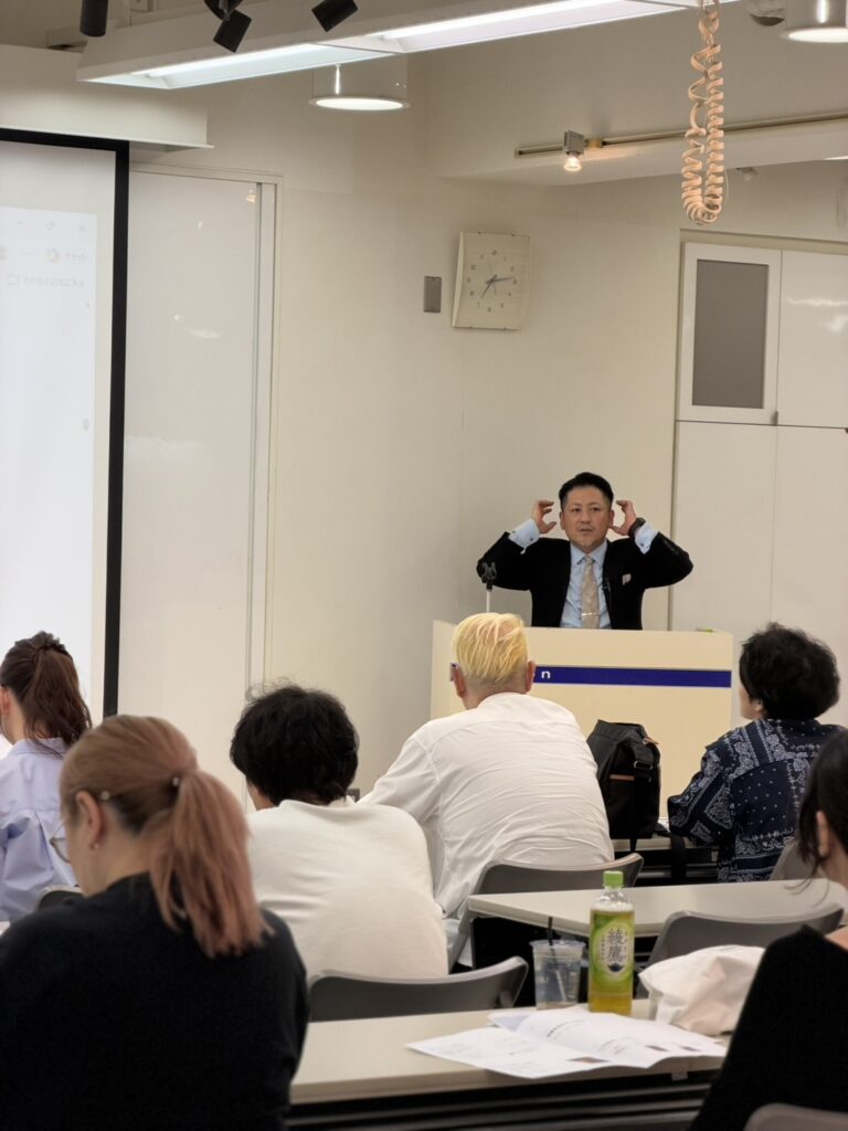 ミルボン大阪支店で頭部に両手を添えながら説明する久保鉄平と受講者